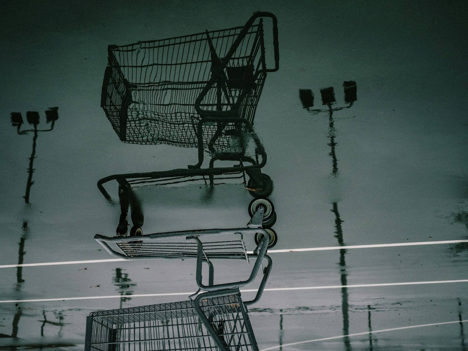 Reflection of a shopping cart in a rainy parking lot